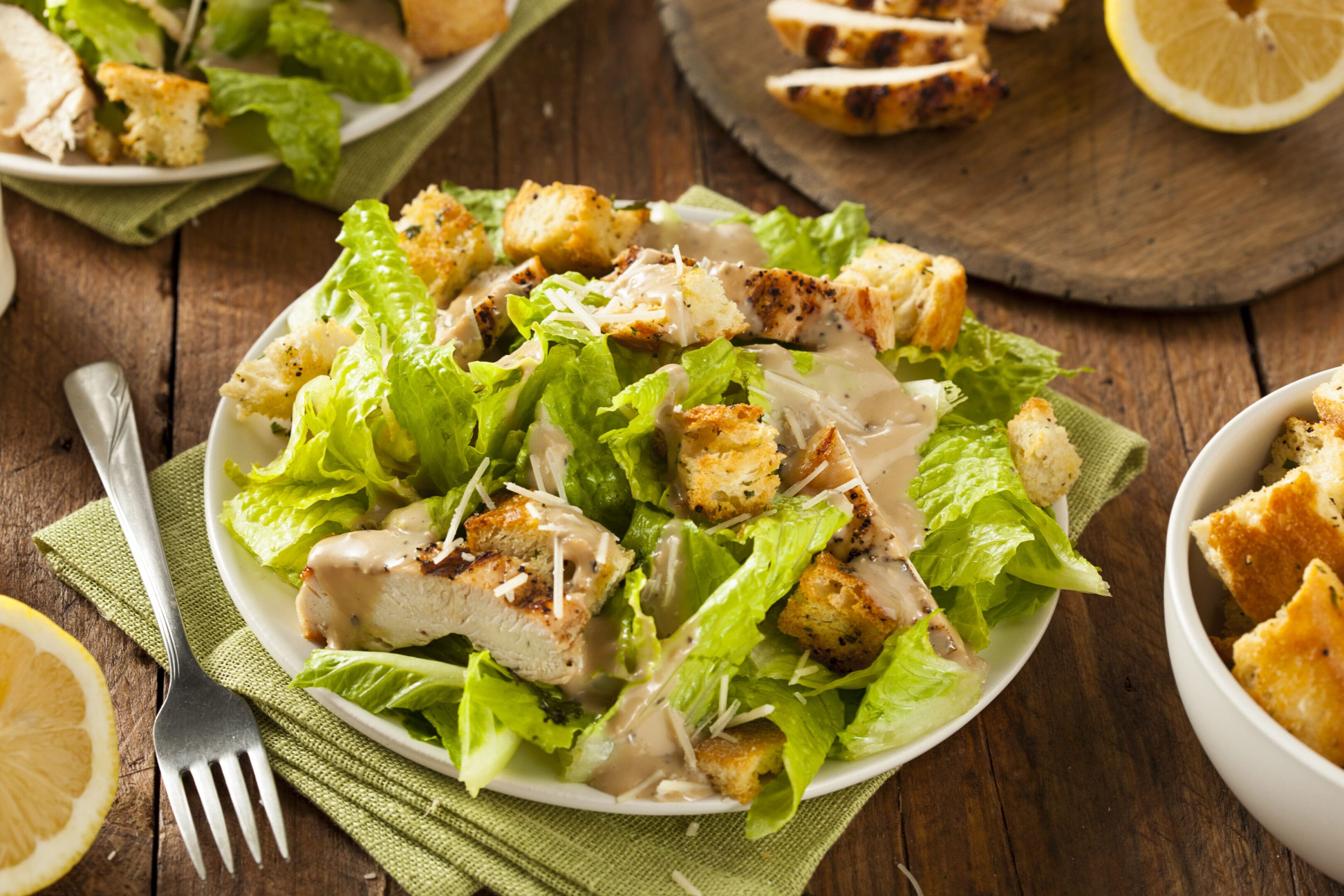 A plate of salad with chicken and croutons.